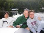 Aunt Kate, Uncle Mike, and my cousin Bailey on the boat with the dock and camp behind them